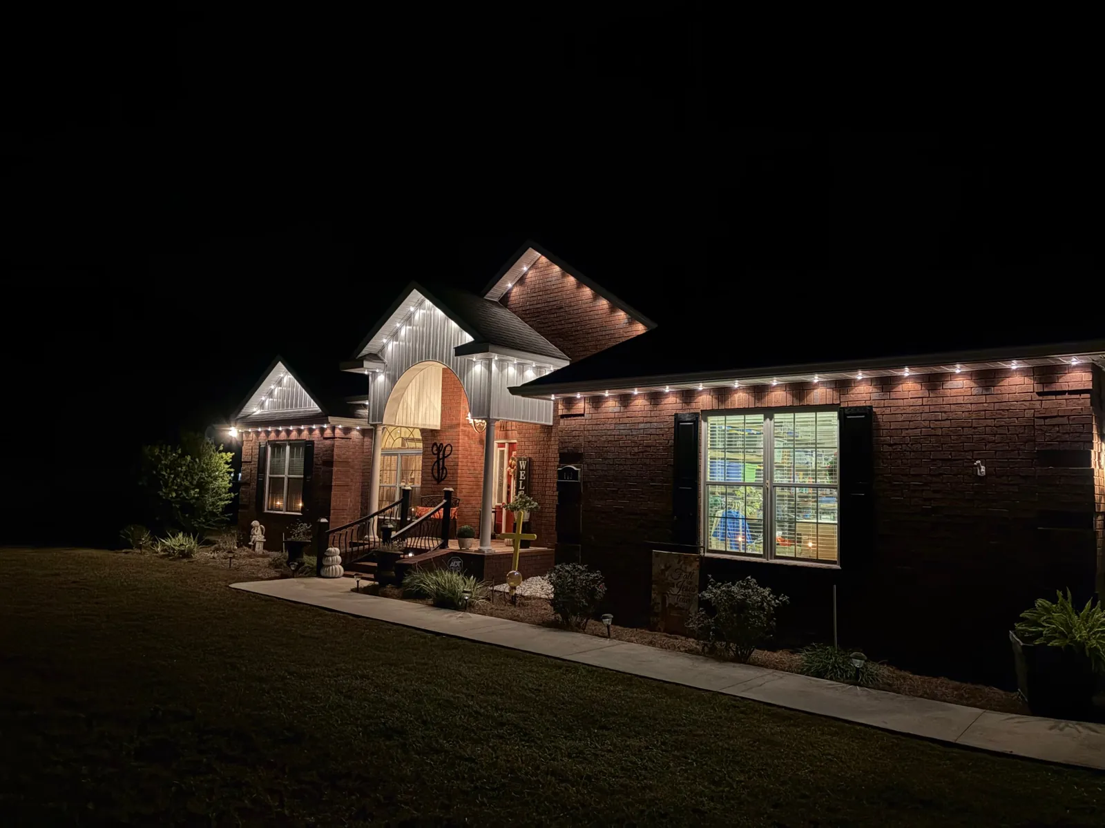 Brick home with warm white permanent roofline lighting at night
